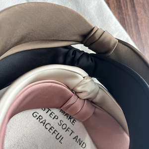 Detail of four satin knotted headbands in brown, black, beige and pink soft fabric