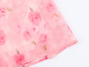 Detailansicht des rosa Blumenmusters mit roten Rosen und feiner Saumverarbeitung