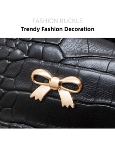 Close-up of golden bow metal buckle on premium black crocodile embossed leather bag