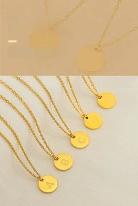 Détail de plusieurs colliers avec pendentifs ronds dorés et lettres sur un tissu