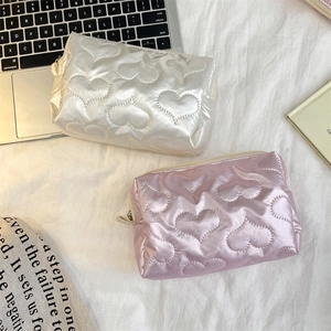 Detailed view of quilted makeup bags in pink and white with embossed heart patterns