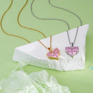 18K gold plated necklace with pink heart pendant displayed on stone decorations