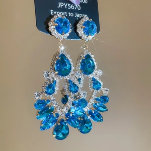 Macro detail of luxurious blue crystal drop earrings with sparkling pear-shaped stones