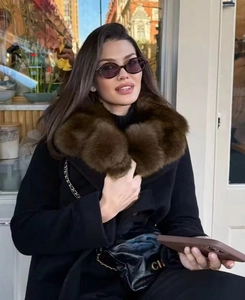 Close-up of elegant black coat featuring a luxurious large brown faux fur collar