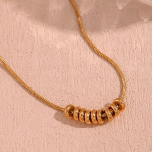 Detail of 18K gold-plated stainless steel snake chain necklace with bean bead pendants