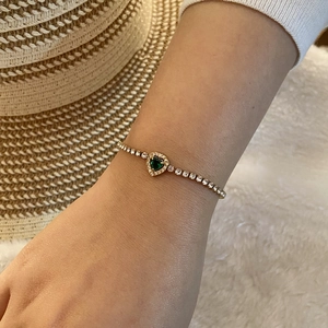 Bracelet doré élégant avec cœur émeraude et pavé de zircons porté au poignet