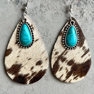 Detail of cowhide leather drop earrings with cow print pattern and turquoise inlay