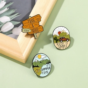 Outdoor adventure enamel pins set featuring mountain and camping themes on a green surface