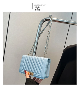 Detail view of light blue quilted shoulder bag featuring gold metal twist lock