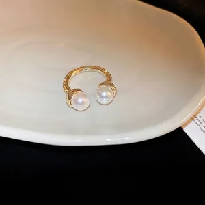 Elegant gold-plated hammered open ring featuring two white pearls on a ceramic plate