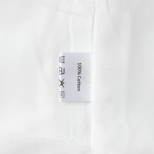 Détail de l'étiquette de lavage 100% coton et de la texture du tissu d'une robe blanche