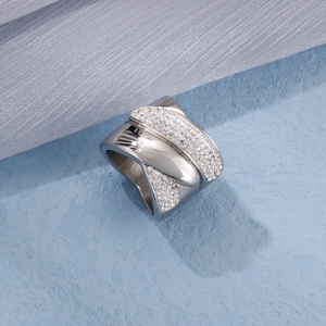 Macro shot of silver wide hollow crisscross ring with pavé diamonds on blue textured stone