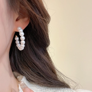 Detail of round pearl hoop earrings on model featuring elegant golden metal clasp and white beads