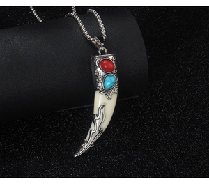 Macro shot of ethnic wolf tooth pendant necklace with red and turquoise gemstones