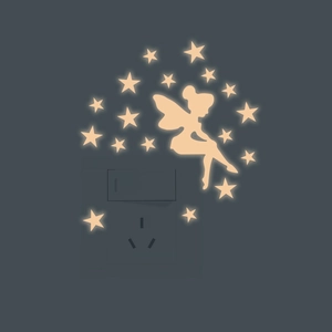 Luminous fairy and stars wall stickers glowing yellow around a light switch on dark wall