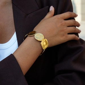 Detailed view of an 18K gold-plated stainless steel cuff with hammered disc texture