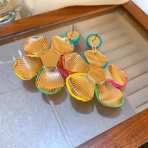 Detail of colorful woven raffia and gold metal flower earrings on a mirror tray