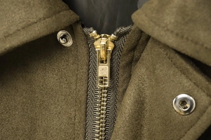 Dettaglio macro del bomber verde militare con zip dorata e bottoni a pressione in argento