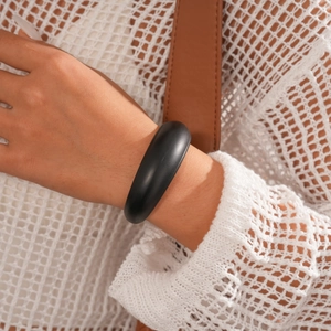 Close-up of minimalist matte black chunky acrylic cuff bracelet on a female wrist