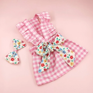 Detalle de vestido rosa a cuadros para perro con accesorio de lazo floral a juego