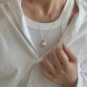 Close-up of minimalist silver pearl necklace worn by a model in casual white outfit