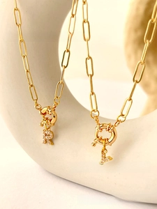Detail of gold letter R and Y necklaces with zircon pavé on white art display