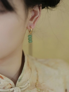 Detail view of handmade gold earrings with three green aventurine beads on model