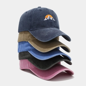 Detail of stacked washed cotton baseball caps showing embroidered mountain sunrise logo