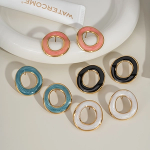 Détail de créoles colorées en émail rose, bleu, noir et blanc avec bordure dorée