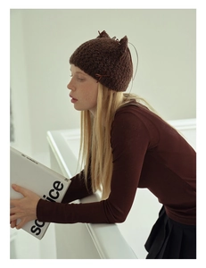 Detailed knit texture of dark brown cat ear beanie with ribbon bows and handmade pattern