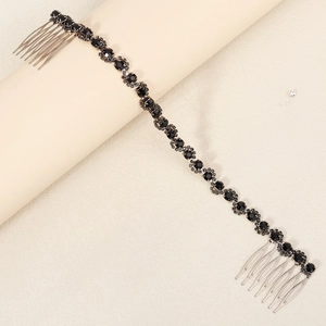 Detail of elegant dark metal hair comb chain with black crystals on beige background