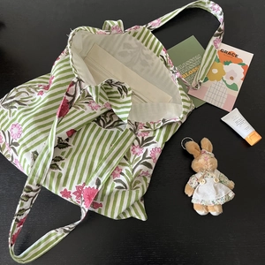Flat lay of canvas tote bag with green stripes, floral print, and interior zipper pocket