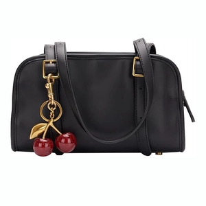 Gros plan sur un sac à main noir en cuir orné d'un pendentif cerise rouge brillant