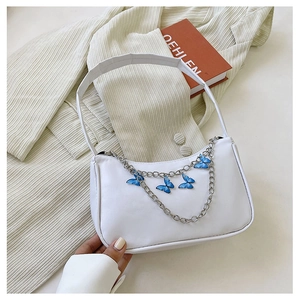 Detail of white underarm bag featuring silver chain and blue butterfly charms