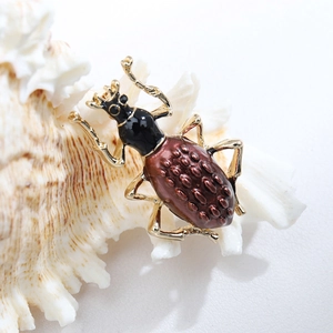 Macro shot of beetle brooch with brown enamel and gold texture on a white shell