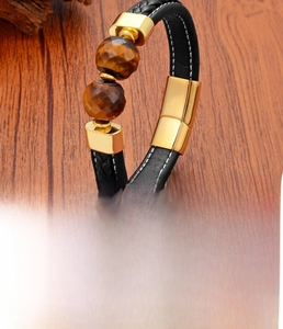 Detail of tiger eye stone beads on braided leather bracelet with stainless steel gold clasp