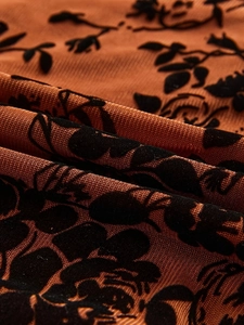 Gros plan sur le tissu en tulle caramel avec motifs floraux floqués noirs et détails