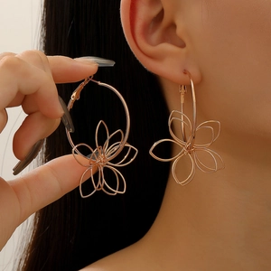 Close-up of model wearing oversized hollow metal flower earrings in rose gold finish