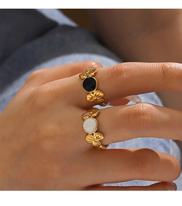 Macro detail of 18K gold-plated stainless steel floral rings with black and white enamel