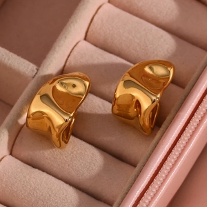 Detailed macro view of gold irregular wavy earrings on pink velvet jewelry box
