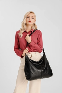 Model wearing a large black leather hobo tote bag with soft vintage style and ample space
