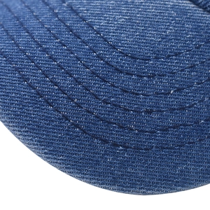 Dettaglio macro della trama in denim lavato e delle cuciture sulla tesa del cappello.