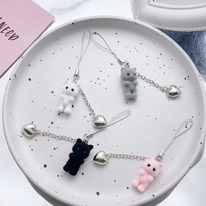 Detail view of colorful flocked kitten charms with heart pendants on a white ceramic tray