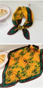 Detail of pleated silk scarf with abstract floral print in orange and dark green