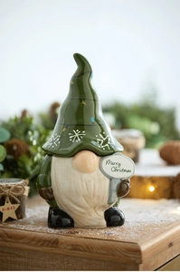 Detail of Christmas ceramic gnome with Merry Christmas sign and snow background