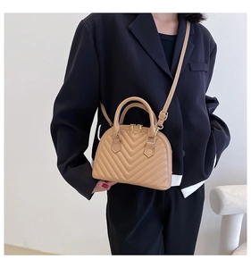 Detail of khaki shell bag with V-quilted stitching and gold metal hardware