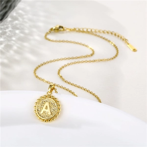 Macro detail of golden stainless steel necklace with round letter A engraved pendant