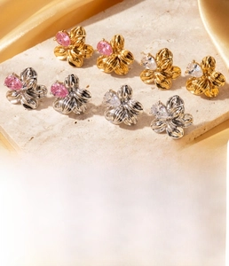 Close-up of floral titanium steel earrings with sparkling zircons and wrinkled metal texture
