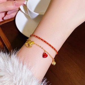 Gros plan d'un bracelet double couche en or 18 carats avec cordon rouge et pendentif cœur