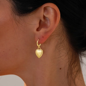 Close-up of 18K gold heart-shaped earrings featuring diamonds on an elegant female model